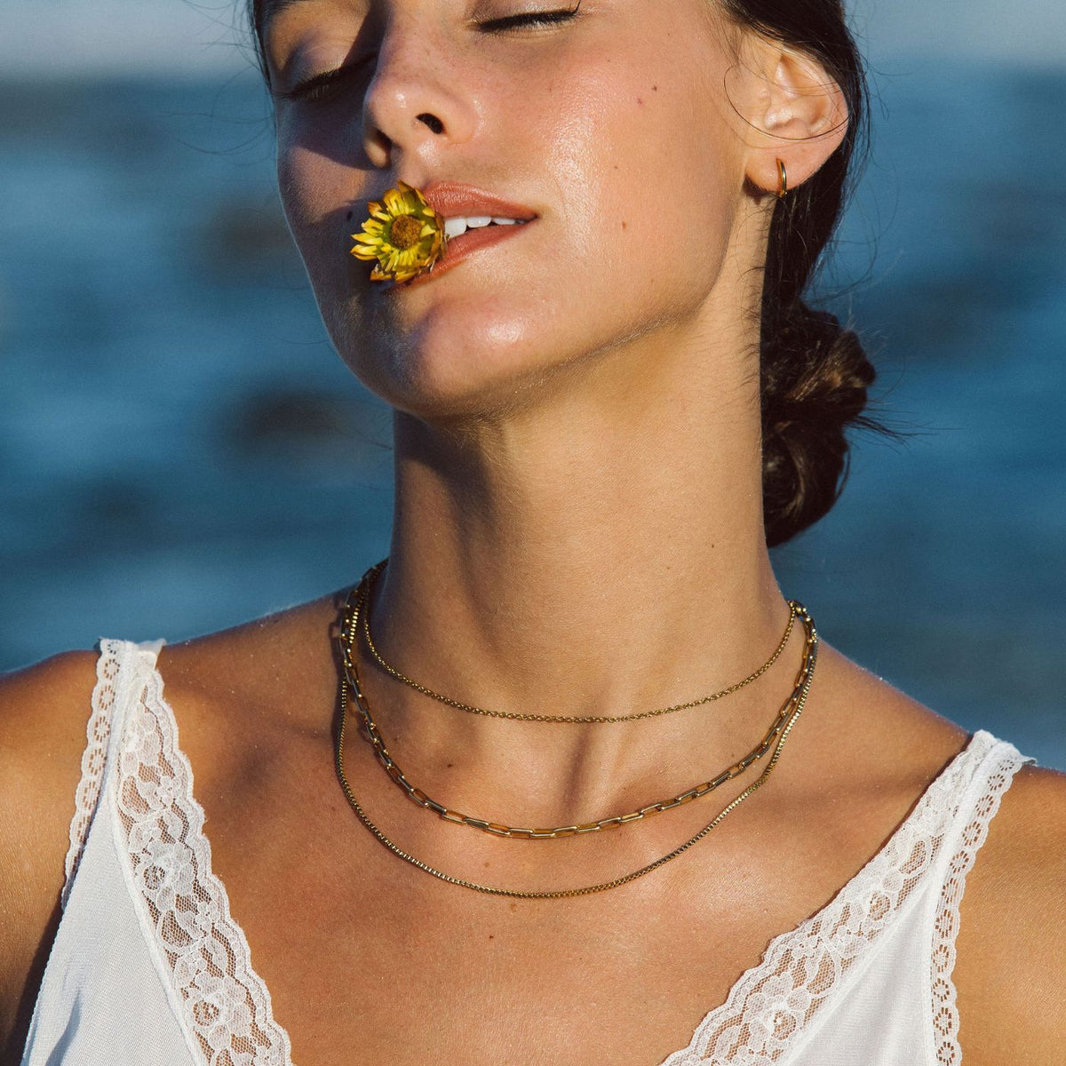 Colar dourado em camadas da Mari Gavane, com detalhes delicados, estilo elegante e moderno, usado no pescoço.