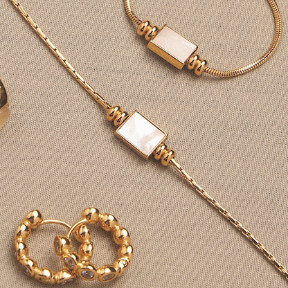 Colar Lune da Mari Gavane com pingente retangular dourado, design minimalista e elegante, sobre fundo branco.